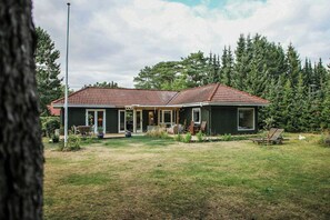 Ein zweigeschossiges Haus mit einer überdachten Terrasse und einem Vorgarten.