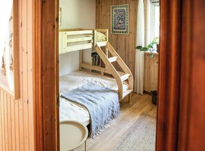 Ein hölzernes Etagenbett mit Bücherregal, ein kleiner runder Tisch und ein gerahmtes Bild an der Wand.