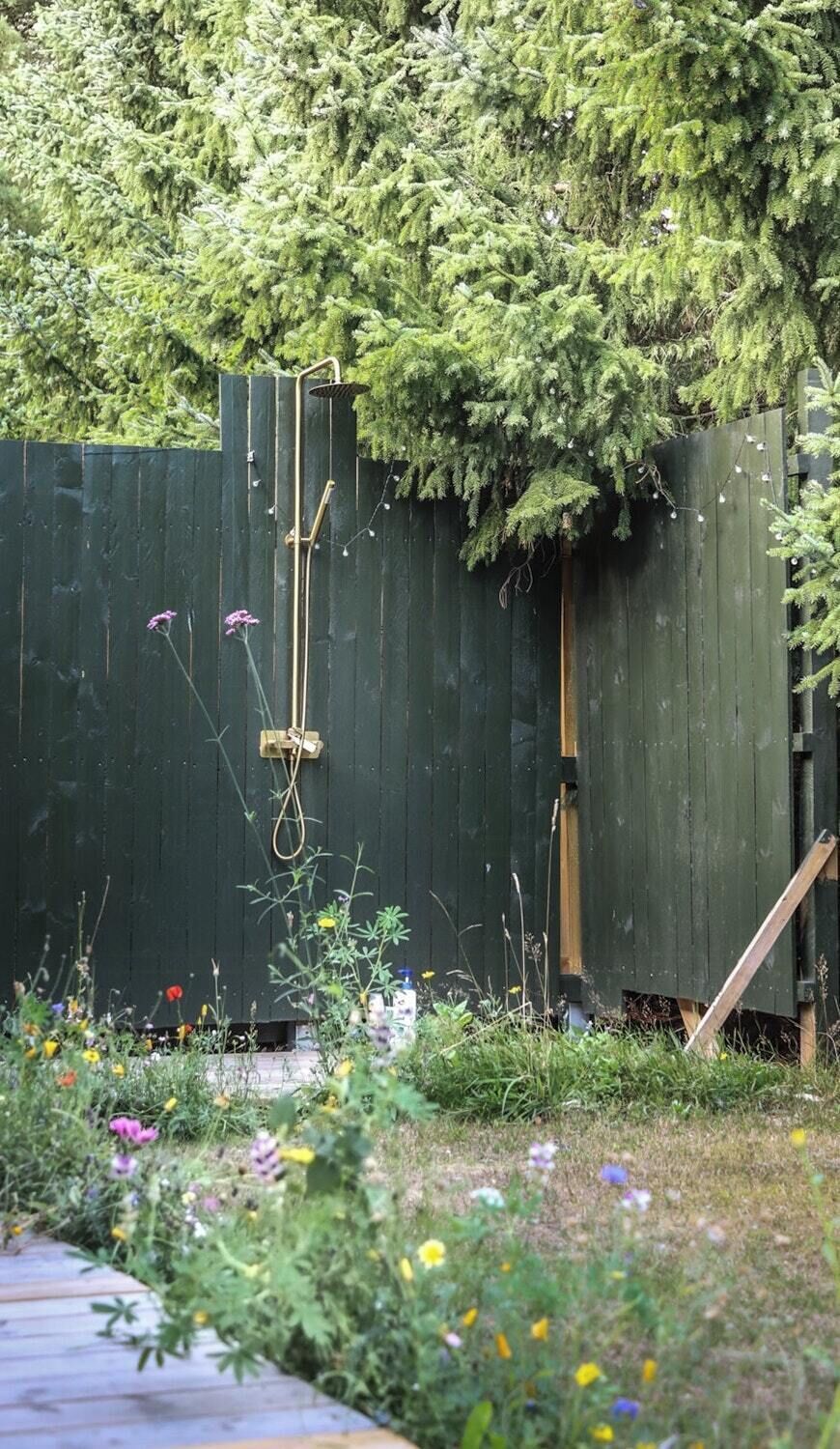 Ein Holzzaun mit daran angebrachtem Metallgeländer, umgeben von einem Garten mit verschiedenen Pflanzen und Blumen.