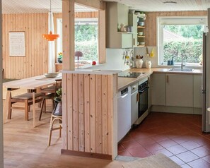 Eine moderne Küche mit Holzelementen, einer zentralen Kochinsel und Blick ins Freie.