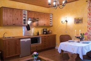 Eine kompakte Küche mit Holzschränken, einem eingebauten Geschirrspüler und einer Essecke mit Tisch für zwei Personen.