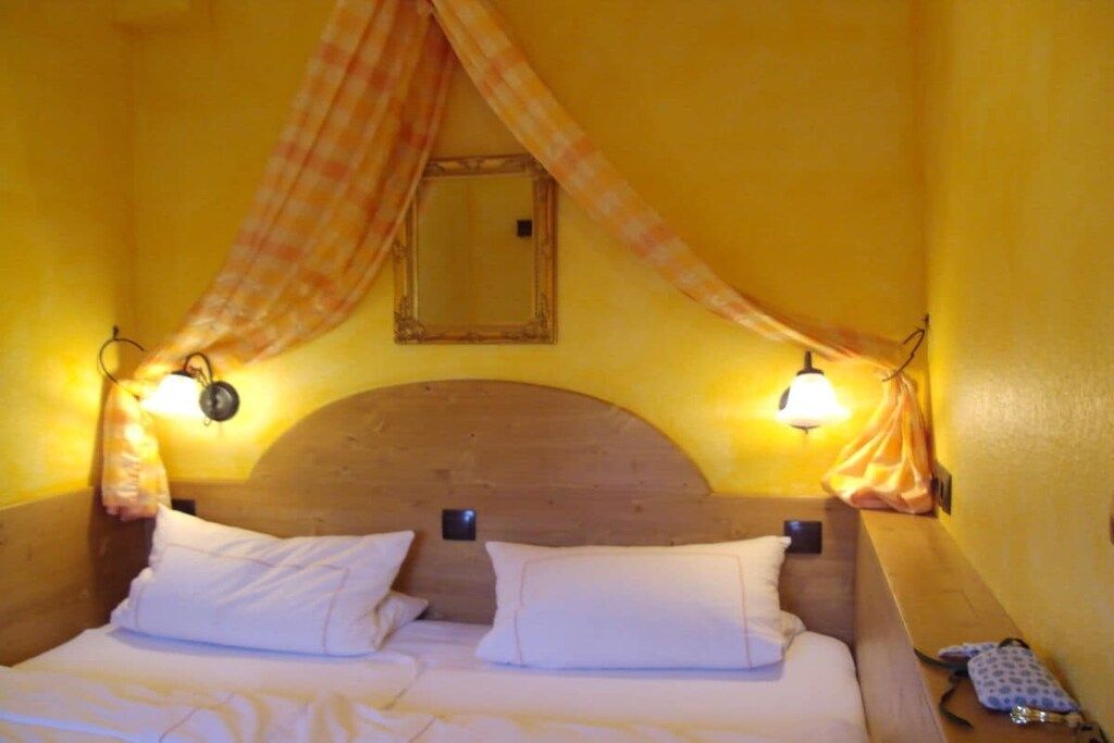 A room with a bed, two wall-mounted lamps, and a canopy.