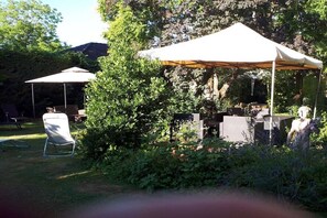 Ein Garten mit Zelt, Stühlen und einer Statue.