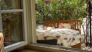 A window view of a table with a floral tablecloth, a wooden chair, and a candle. - Holiday apartment with 1 bedroom (Freinsheim)