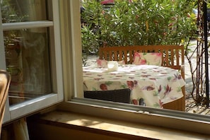 A window view of a table with a floral tablecloth, a wooden chair, and a candle. - Holiday apartment with 1 bedroom (Freinsheim)