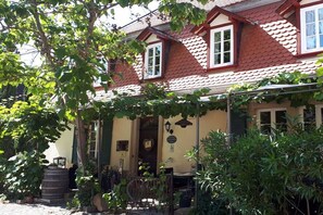 A building with a red-tiled roof, a porch with a bench, and a barrel. - Holiday apartment with 1 bedroom (Freinsheim)