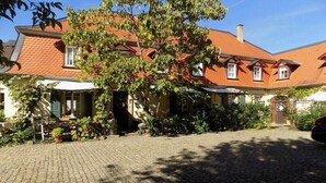 A traditional European house with a cobblestone driveway, a large tree in front, and a red-tiled roof. - Holiday apartment with 1 bedroom (Freinsheim)