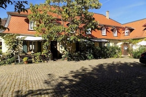 A traditional European house with a cobblestone driveway, a large tree in front, and a red-tiled roof. - Holiday apartment with 1 bedroom (Freinsheim)
