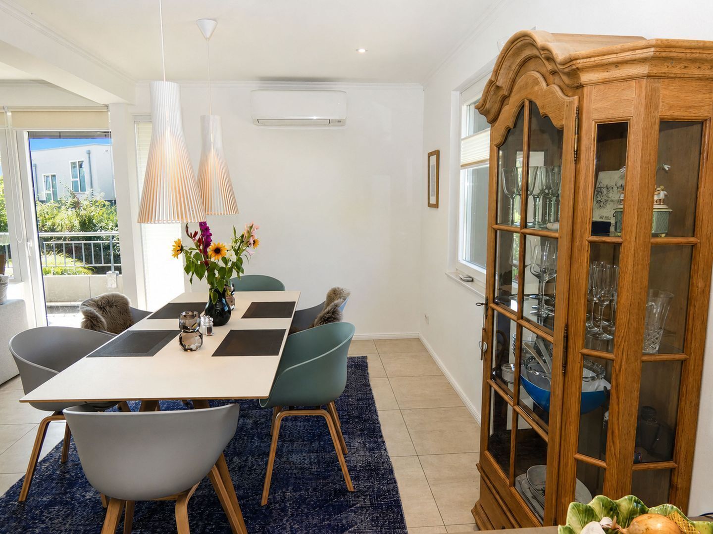 A dining area with a table, chairs, and a cabinet with glass doors.