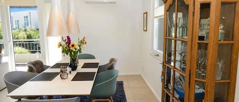 Zona pranzo con tavolo, sedie e un mobile con ante in vetro.