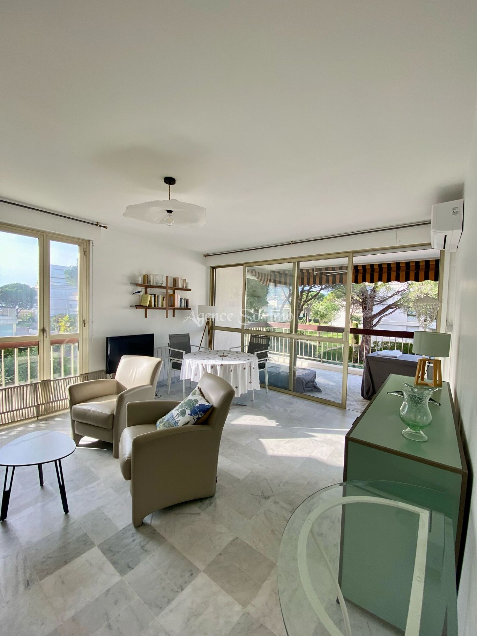 Ein großzügiger Wohnbereich mit Balkon, Fernseher und Bücherregal.