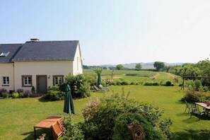 A house with a large garden, a wooden bench, and a table with chairs. - Holiday apartment with 2 bedrooms (Jucken)