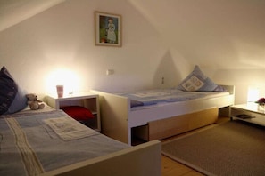 A bedroom with two beds, a nightstand, a lamp, and a painting on the wall. - Holiday apartment with 2 bedrooms (Jucken)