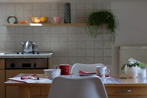 A kitchen with a kettle, a clock, and a shelf with fruits and a plant. - Holiday apartment with 2 bedrooms (Jucken)