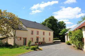 Un bâtiment à deux étages avec une allée en gravier et un petit jardin.