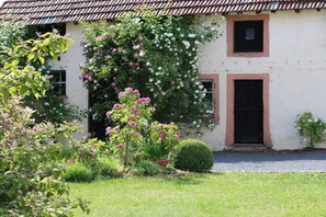 A building with a garden in front, a door, and a window. - Holiday apartment with 2 bedrooms (Jucken)