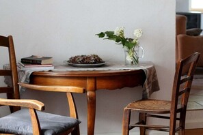 A wooden dining table with a vase of flowers, a plate of food, and a stack of books. - Holiday apartment with 2 bedrooms (Jucken)