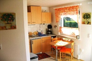 Eine kompakte Küche mit Holzausstattung, einer Spüle und einem Essbereich mit Tisch und Stühlen.