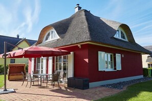 A house with a red exterior, a thatched roof, and a patio area with outdoor furniture. - ||------------Lucky Glowe-----------------------|| (Glowe)