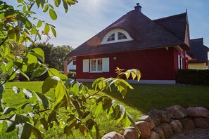 A red house with a dark roof, surrounded by a well-maintained lawn and a stone wall. - ||------------Lucky Glowe-----------------------|| (Glowe)