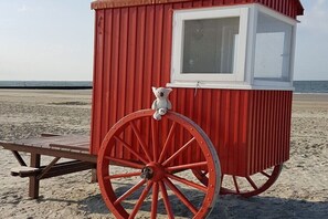 A red lifeguard tower with a white window and a teddy bear on top, situated on a sandy beach. - 4 in the Kiebitzwiese house (Borkum)