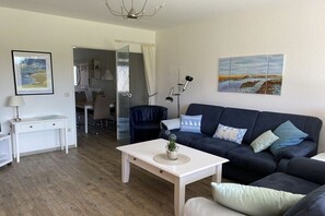 A modern living room with a dark sofa, a white coffee table, and artwork on the walls. - 4 in the Kiebitzwiese house (Borkum)
