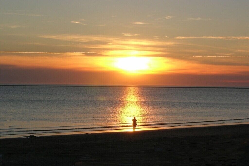 A person standing on a beach during sunset.