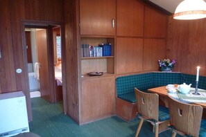 A room with a wooden cabinet, a green checkered bench, and a table with chairs. - Holiday apartment in Kirchbrak with parking (Kirchbrak)