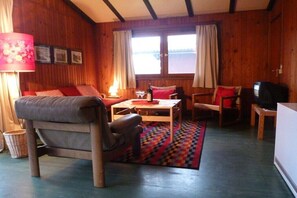 A cozy room with a sofa, a table, and a television. - Holiday apartment in Kirchbrak with parking (Kirchbrak)