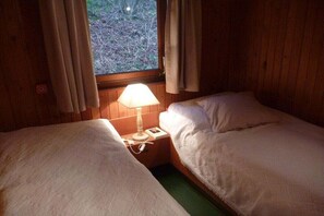 A room with two beds, a window with curtains, and a bedside lamp. - Holiday apartment in Kirchbrak with parking (Kirchbrak)