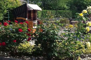 A garden with a wooden bench, a birdhouse, and various flowering plants. - Holiday apartment with 1 bedroom (Wiesmoor)
