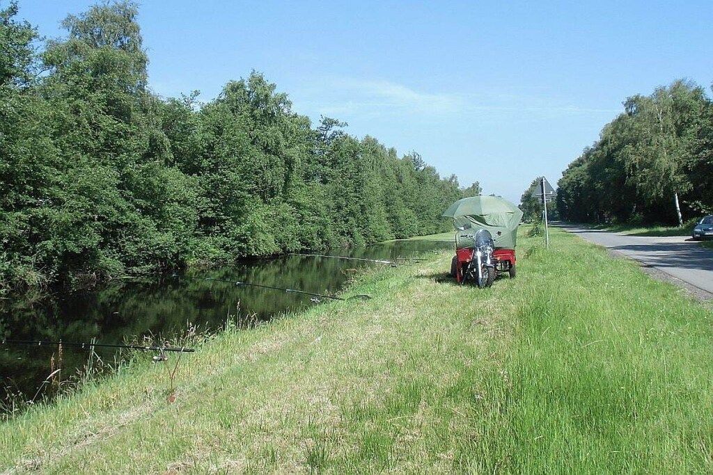 Orilla de río con un barco a motor y un remolque.