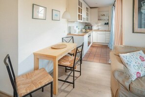 Un espace de vie compact comprenant un coin repas, une kitchenette et un canapé.