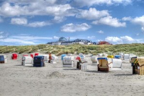 Une plage avec des chaises de plage et un grand bâtiment en arrière-plan.