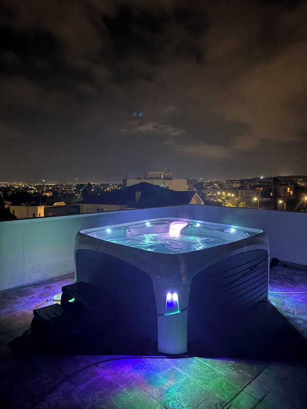A hot tub with a water feature on a rooftop terrace with a cityscape view in the background.