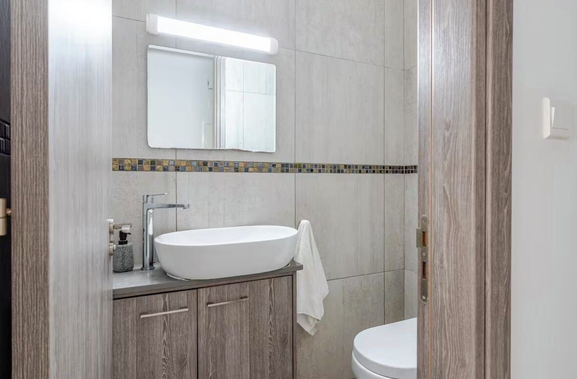 Une salle de bain avec un lavabo blanc, un miroir et des toilettes.