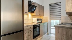 Cuina moderna amb forn integrat, microones i nevera d'acer inoxidable.