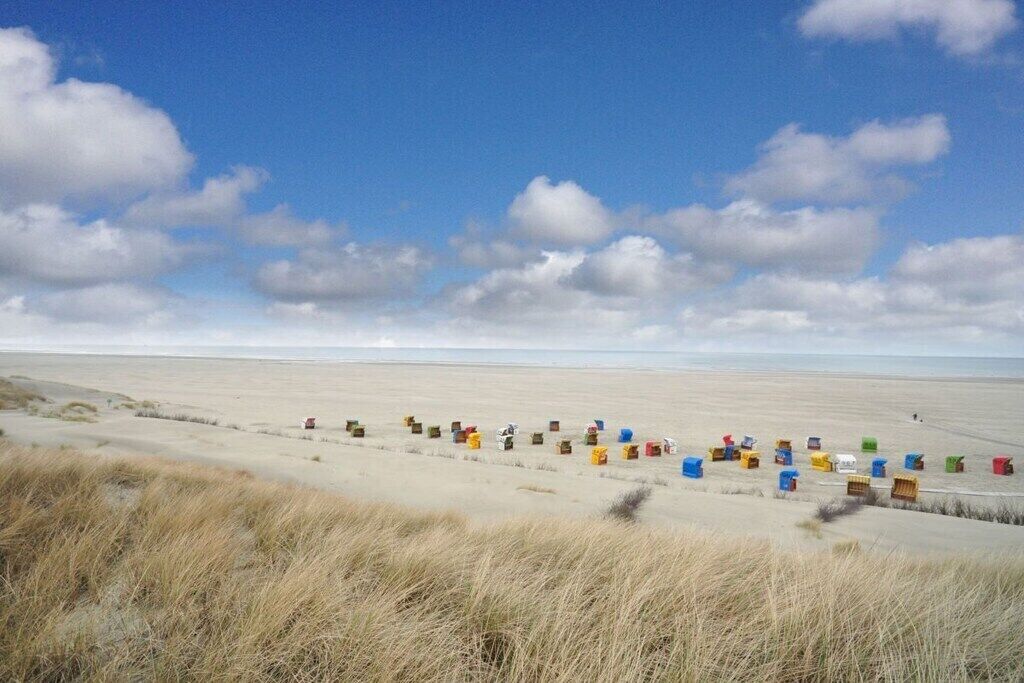 A beach with a row of colorful containers lined up on the sand.