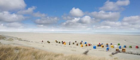 A beach with a row of colorful containers lined up on the sand.