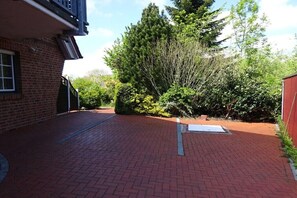 A paved courtyard with a brick pathway, surrounded by dense greenery and trees. - in the middle of an organic fruit farm (Elbinsel Krautsand)