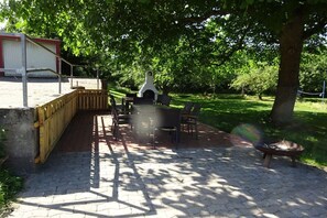 An outdoor patio with a brick floor, a wooden fence, and a grill area. - in the middle of an organic fruit farm (Elbinsel Krautsand)