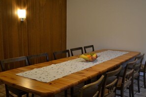 Ein Holzespeisesaal mit einer Tischdecke mit Blumenmuster, umgeben von Holzstühlen.