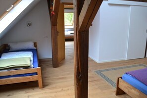 Ein Zimmer mit zwei Holzbetten, einem Oberlicht und Blick ins Freie.