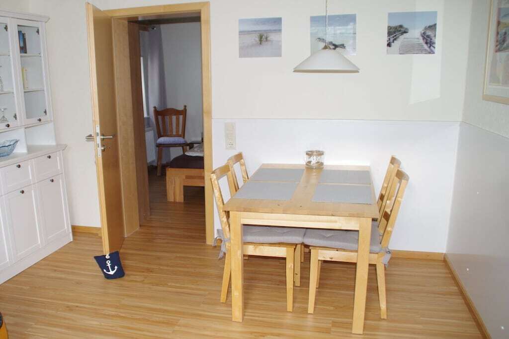 A dining area with a wooden table and chairs, a cabinet with glass doors, and a door leading to another room.