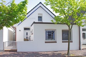 Ein weißes Gebäude mit einem Satteldach, einem kleinen Fenster und einer Tür.