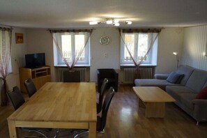 Ein Wohnzimmer mit einem Holzesstisch, einer Couch, einem Fernseher und einer Heizung.
