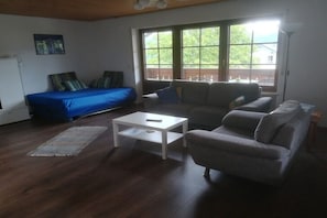 A living room with a sofa, a coffee table, and a window with a view. - Holiday apartment with 1 bedroom (Kleines Wiesental - Sallneck)