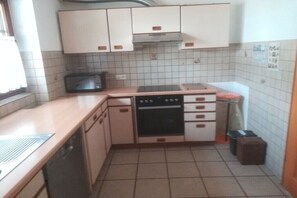 Eine kleine Küche mit weißen Schränken, einer Mikrowelle, einem Backofen und einem Spülbecken.