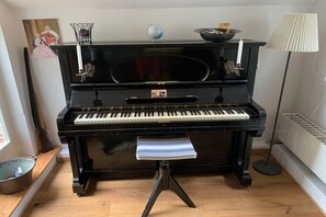 A black upright piano with a bench, a globe, and a candle on top.