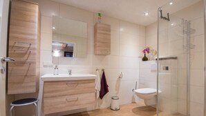 Ein modernes Badezimmer mit Duschkabine aus Glas, einem Holzwaschtisch und einem мраморной Waschbecken.